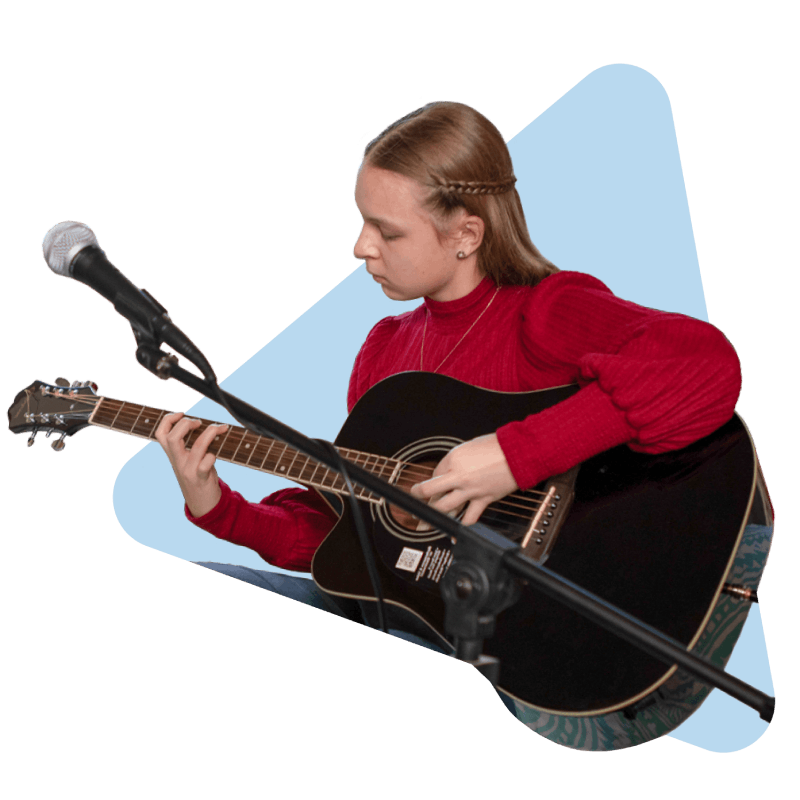 A young girl joyfully strumming an acoustic guitar, immersed in her music and creativity.